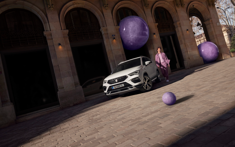 Weißer SEAT Ateca und Mann in violettem Anzug vor einem historischen Gebäude