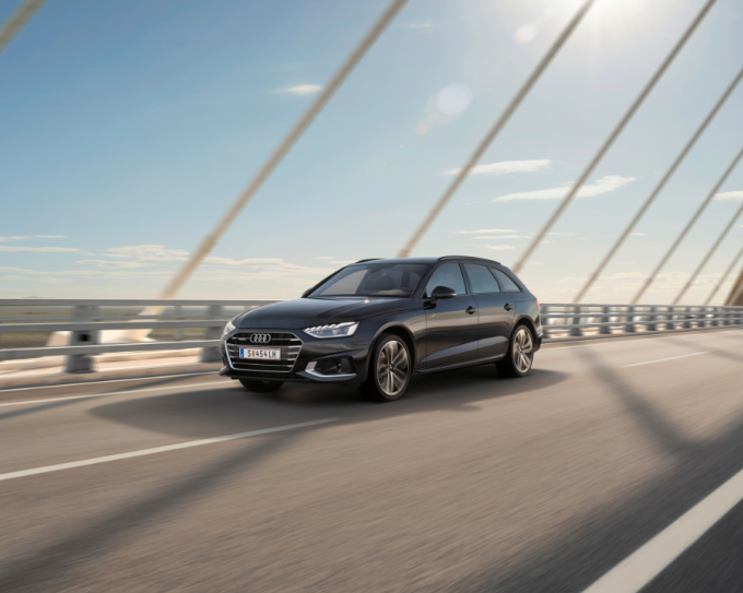 Dunkler Audi A4 fährt über eine Brücke bei sonnigem Wetter