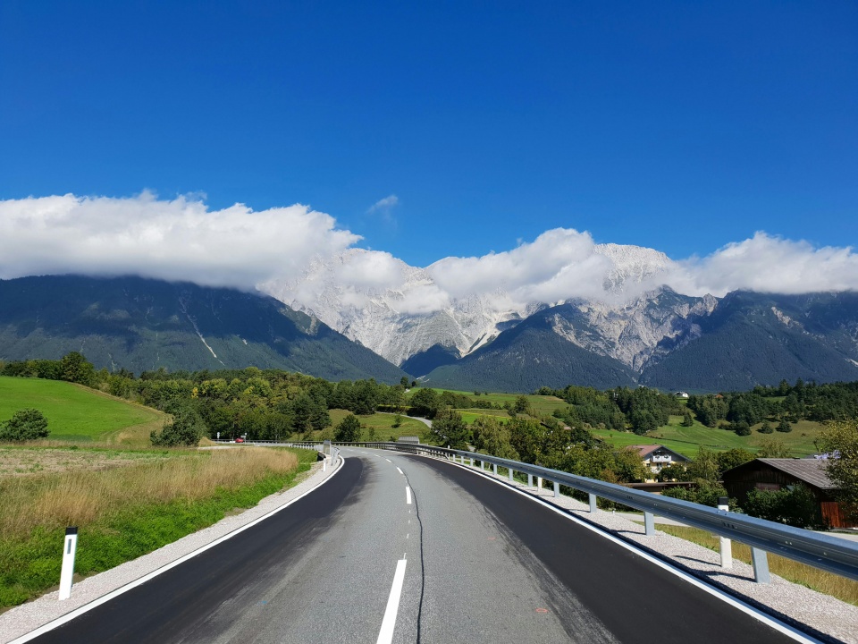 Eine kurvenreiche Straße, die von beeindruckenden Bergen umgeben ist, die in der Ferne sichtbar sind.