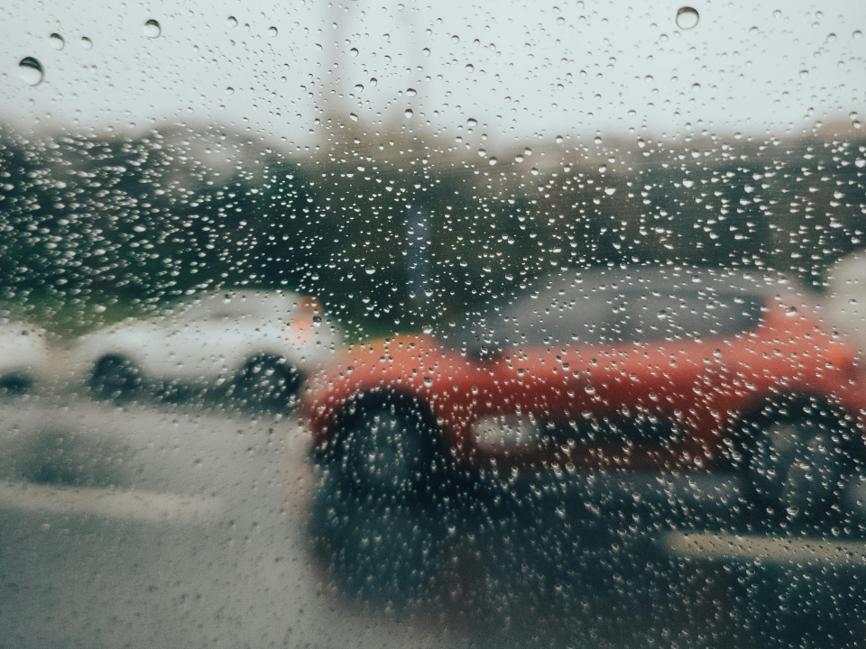 Blick durch eine Autoscheibe mit Wassertropfen auf vorbeifahrende Fahrzeuge
