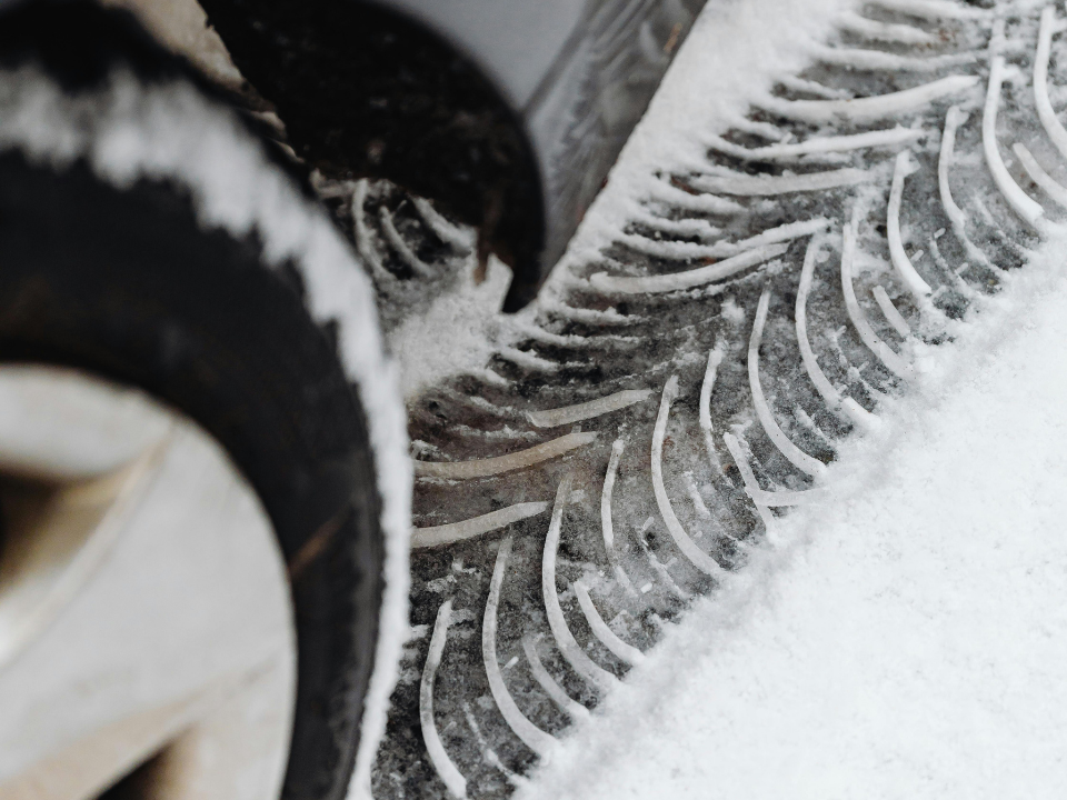 Nahaufnahme eines Autoreifens mit Winterprofil im frischen Schnee