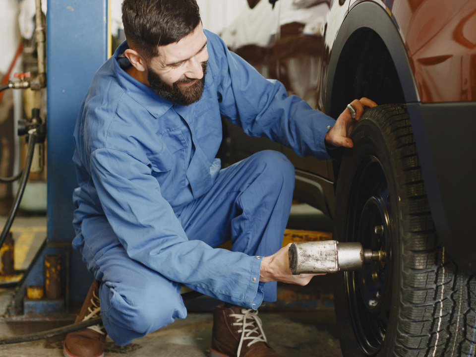 Ein Mann zieht die Schrauben eines Autoreifens in einer Werkstatt an