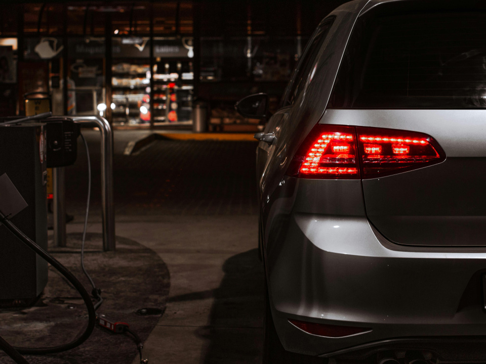 Heckansicht eines silbernen VW an einer Zapfs&auml;ule bei Nacht