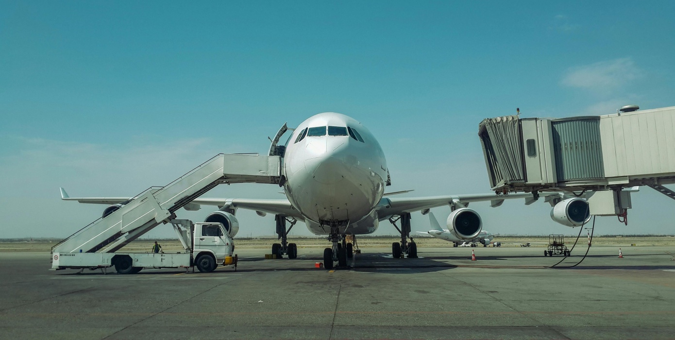 Ein großes Passagierflugzeug steht am Flughafen mit einer Fluggastbrücke und einer mobilen Treppe.