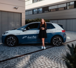 Frau lehnt an der Fahrertür eines sharetoo-Fahrzeugs