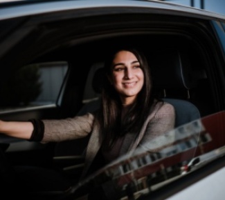 Frau lacht aus dem halb geöffneten Fahrerfenster