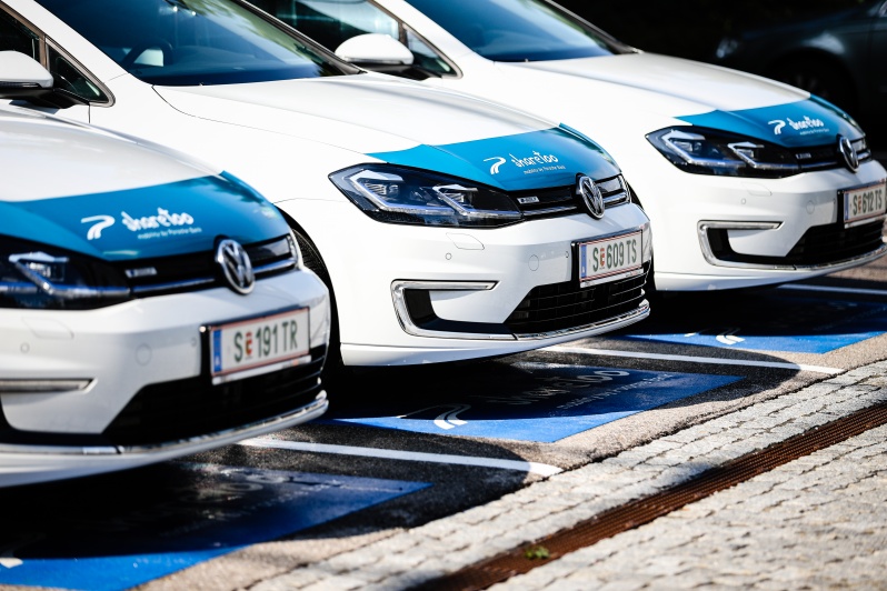 3 weiße Volkswagen mit blauem sharetoo-Schriftzug auf der Motorhaube mit Salzburger Kennzeichen