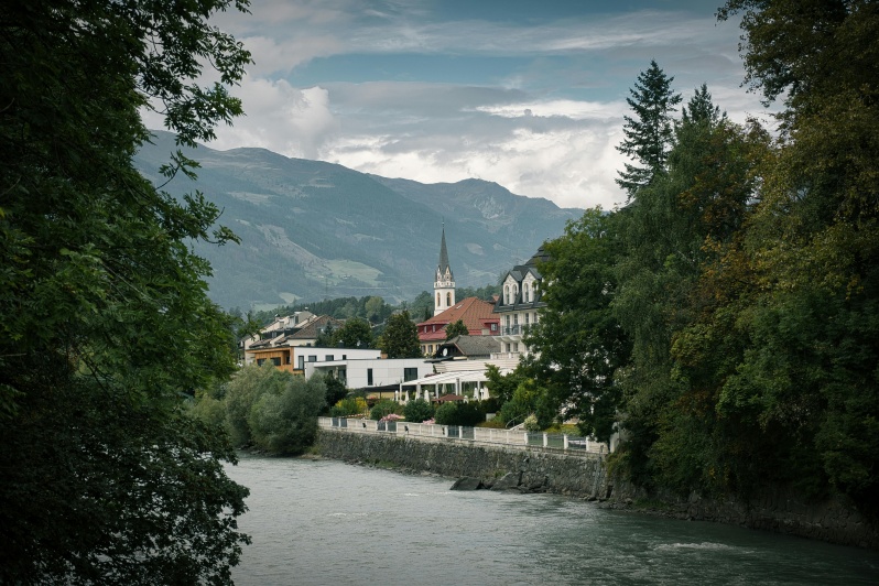 Die Drau fließt durch Lienz, umgeben von Gebäuden und Bäumen, die die Ufer säumen.