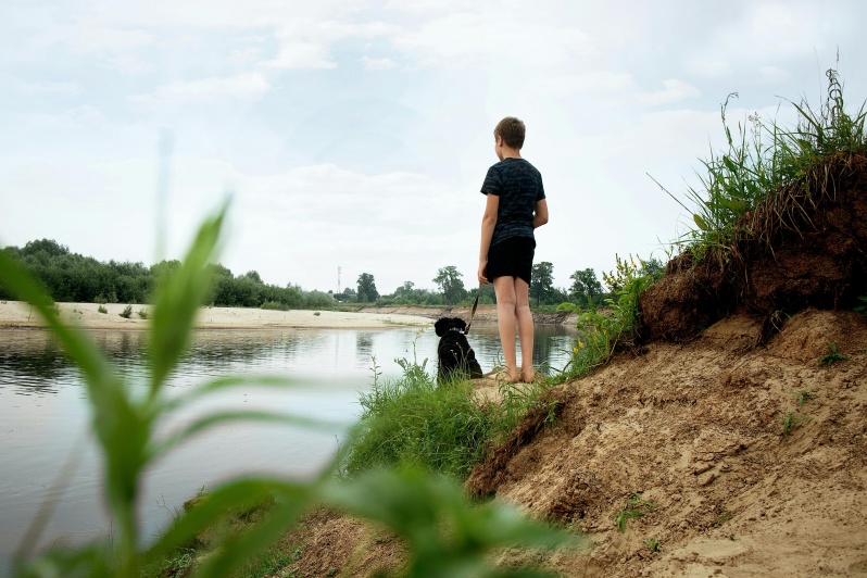 Am Donauufer stehendes Kind mit Hund.