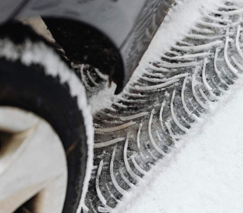 Blick auf einen Autoreifen, der einen Profilabdruck im Schnee hinterl&auml;sst